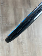 Close-up of a "Pasela" tire on a rim against a wood floor—crafted with precision like a pre-owned Babolat Pure Drive VS (4 3/8), a racquet renowned for power and spin.