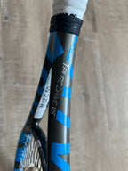 Close-up of the pre-owned Babolat Pure Drive VS 4 3/8 tennis racquet, featuring its branded frame and renowned power and spin, displayed on a wooden floor.