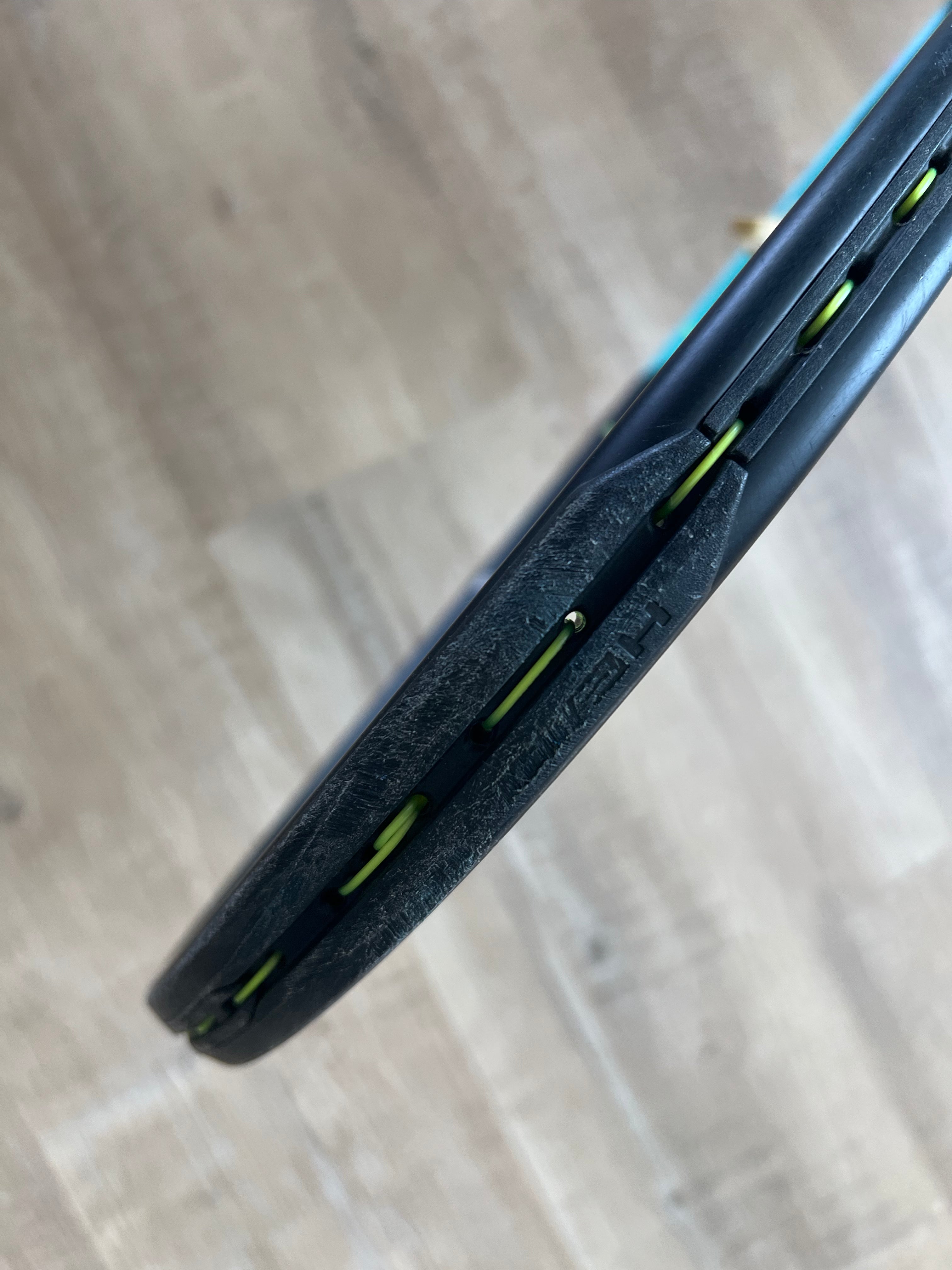 Close-up of a pre-owned Head Boom Pro 2022 (4 1/4) tennis racquet in black with green strings, showing some frame wear—perfect for aggressive players seeking high performance.